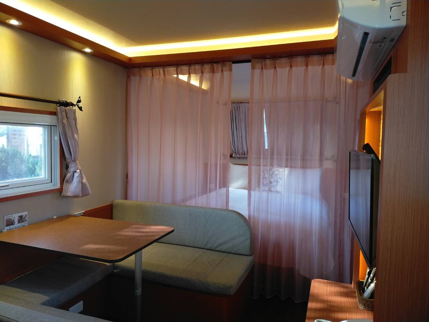 A compact room with a bed, a small table, and a TV.