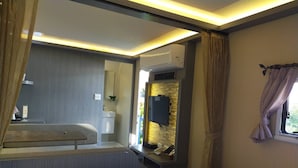 A modern bedroom with a bed, a vanity with a mirror, a sink, and a window with curtains. - K-1 Hotel (Yuanlin)
