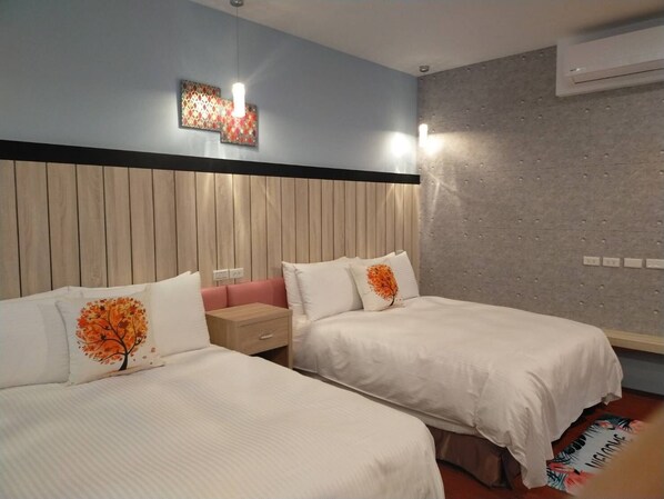 A hotel room with two beds, a wooden headboard, a small nightstand, and a wall-mounted air conditioner.