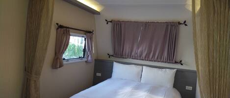 A bedroom with a bed, a window with curtains, and a ceiling light.