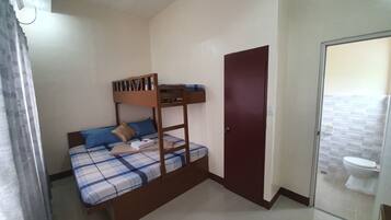 A small, simple room with a bunk bed, a door, and a bathroom visible through a glass partition.