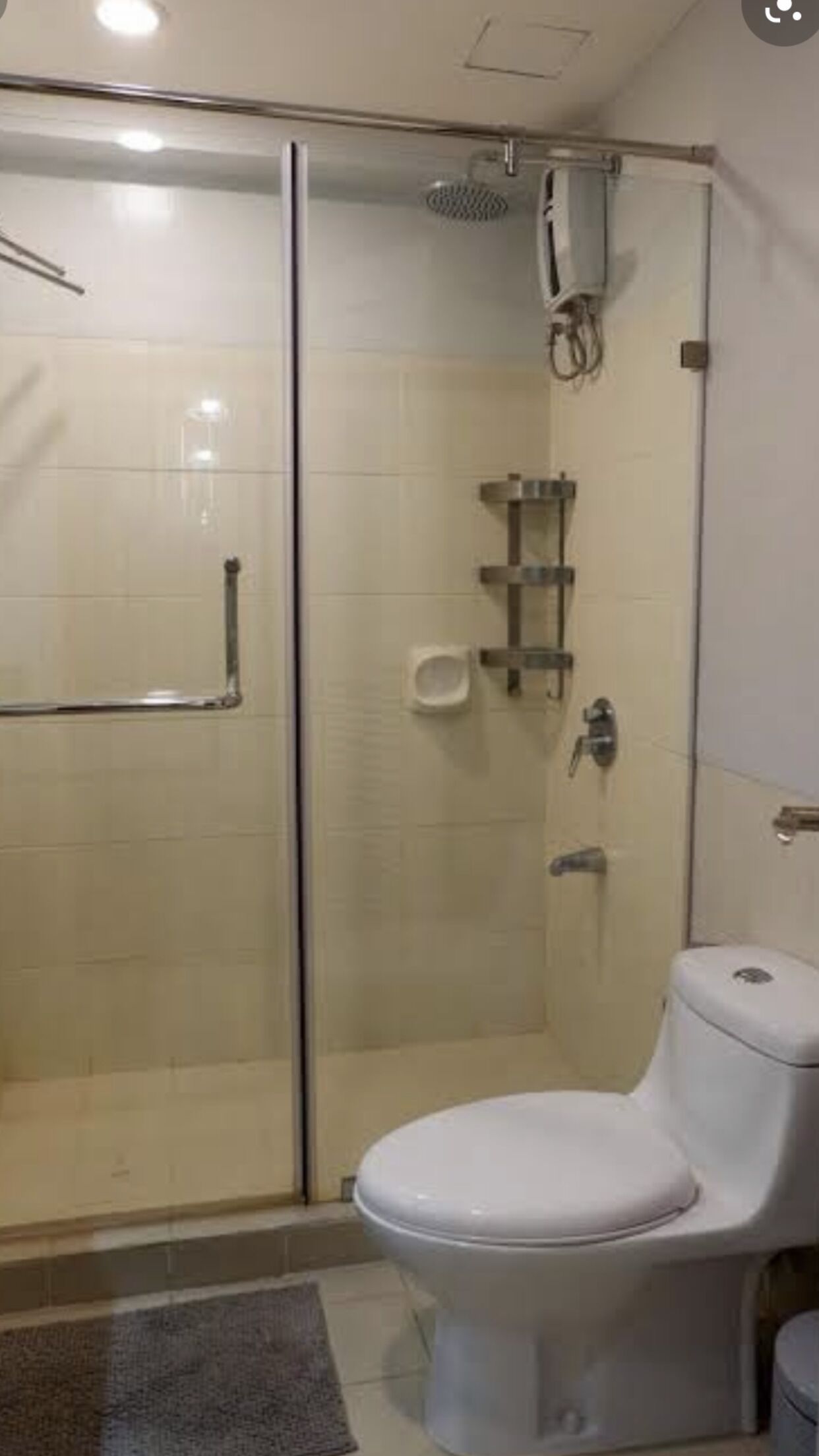 Un baño con ducha de vidrio, inodoro y barra para toallas.