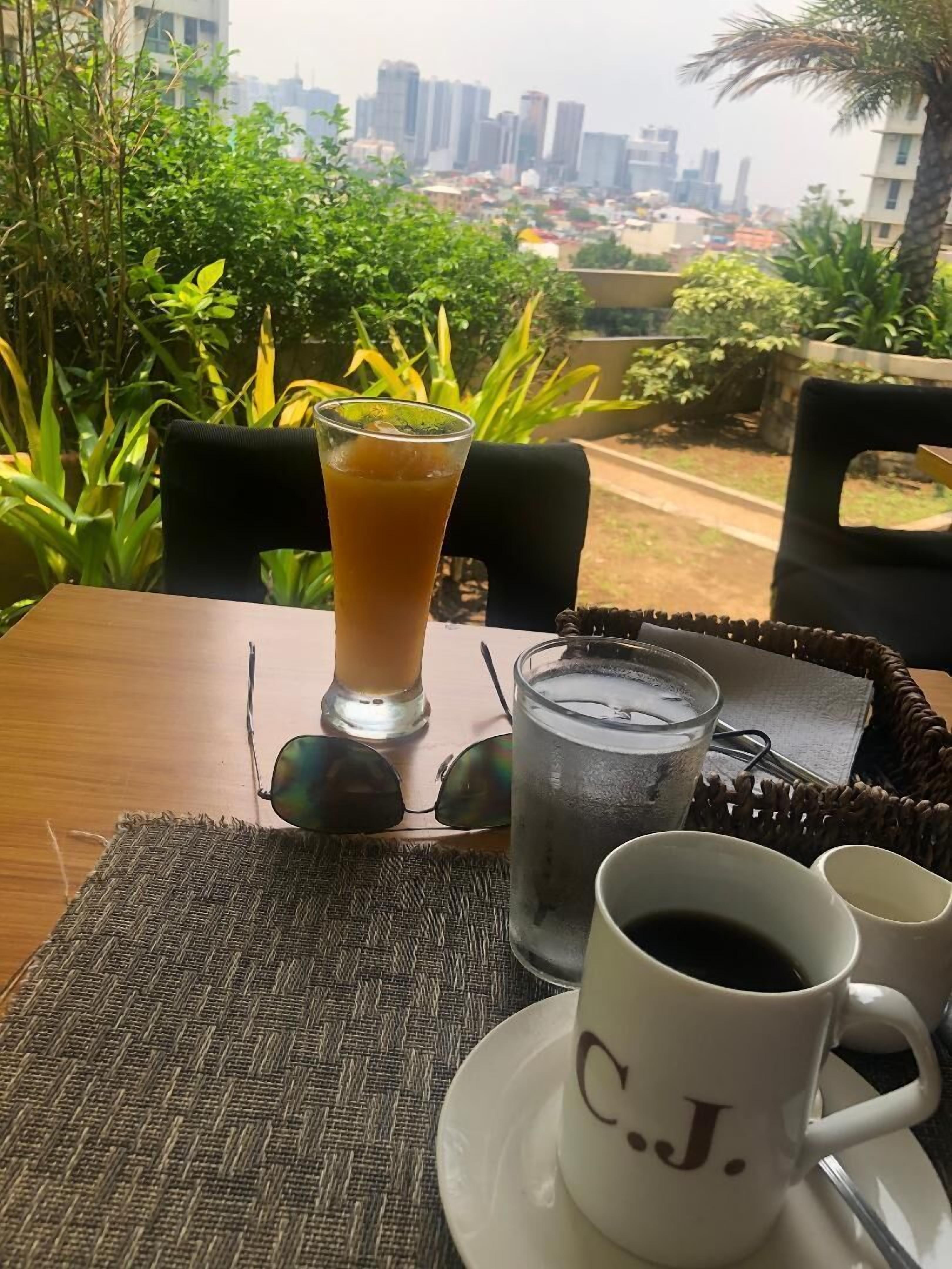 A table with a drink, a glass of water, a cup of coffee, and a mug with initials.