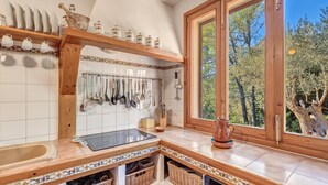 A kitchen with a wooden countertop, a sink, a window with a view of trees, and a hanging utensil rack. - Beautiful Holiday Home Miravall with Mountain View (Puigpunyent)