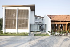 A modern building with large windows, a covered outdoor seating area, and a well-maintained lawn.