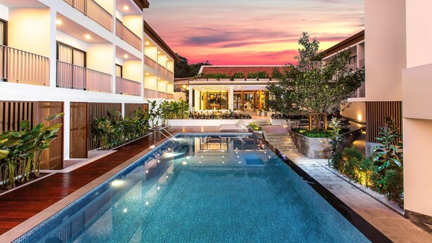 A modern hotel with a swimming pool, multiple balconies, and a well-lit outdoor area. - Sook Hotel (Ranong)