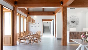 A modern hotel lobby with wooden beams, wicker furniture, and a reception desk with a logo. - Sook Hotel (Ranong)