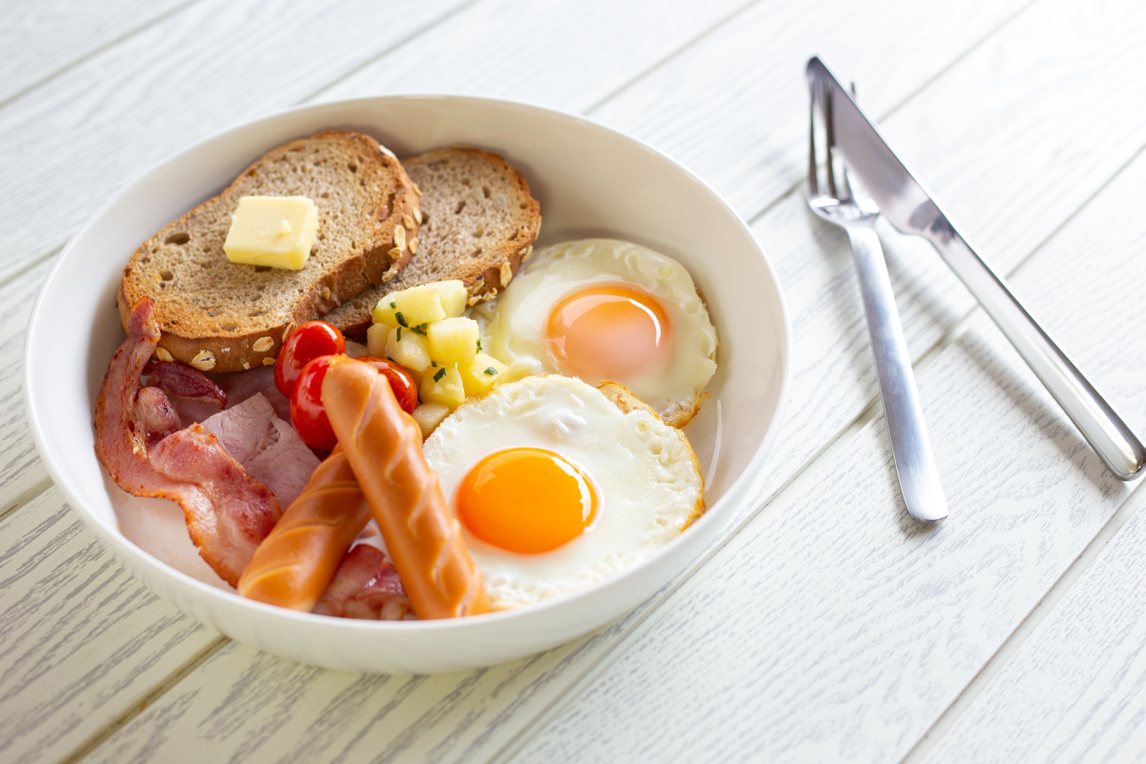 A breakfast plate with toast, eggs, bacon, and tomatoes.