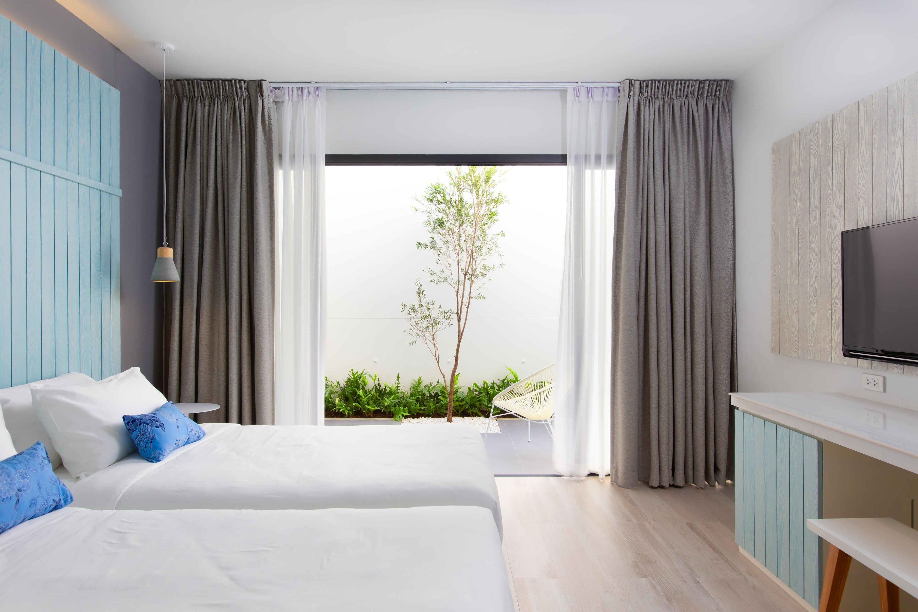 Una habitación de hotel moderna con una cama grande, un televisor y vistas a zonas verdes.