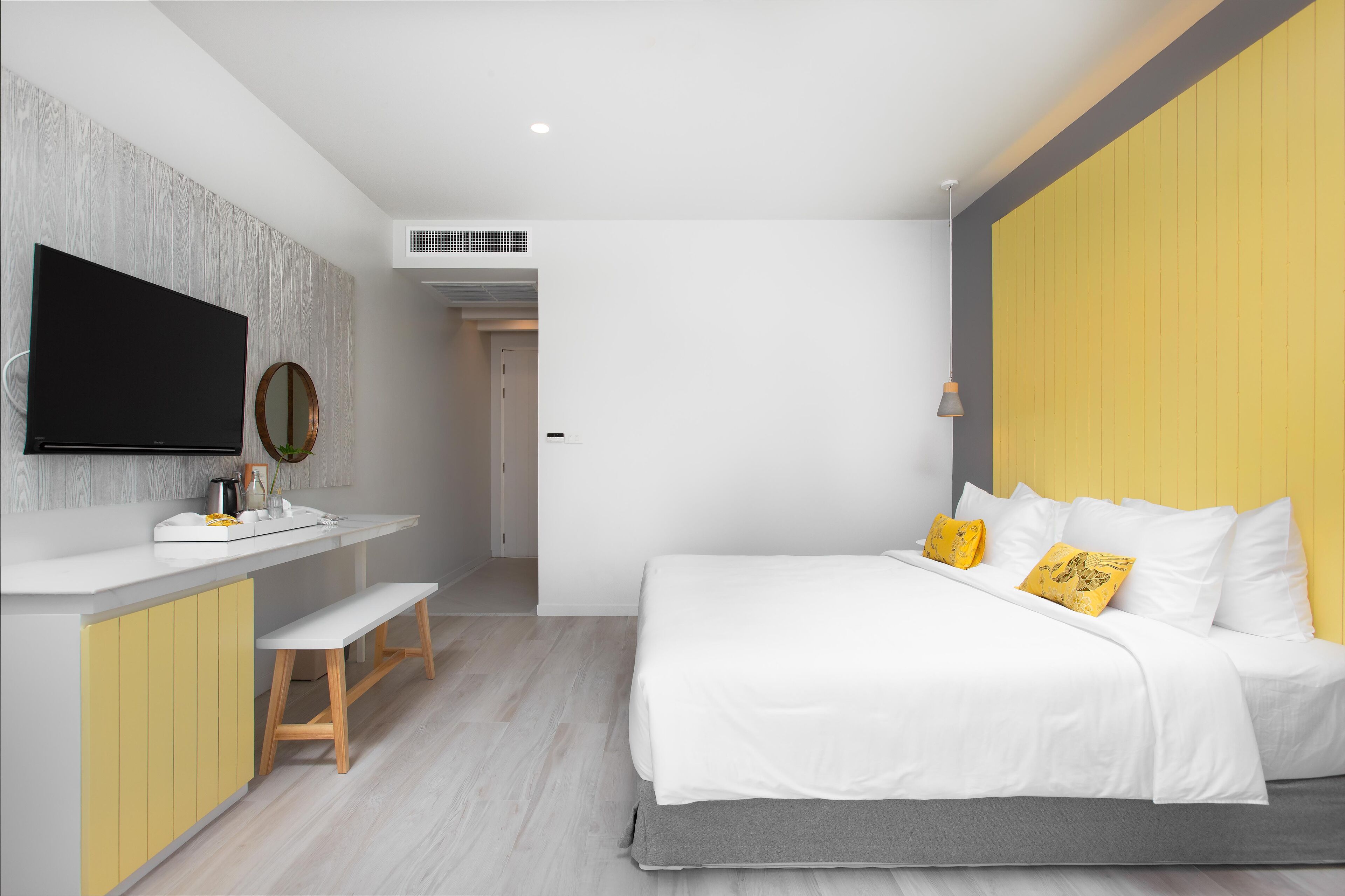 A modern bedroom with a bed, bedside table, and a flat-screen TV mounted on the wall.