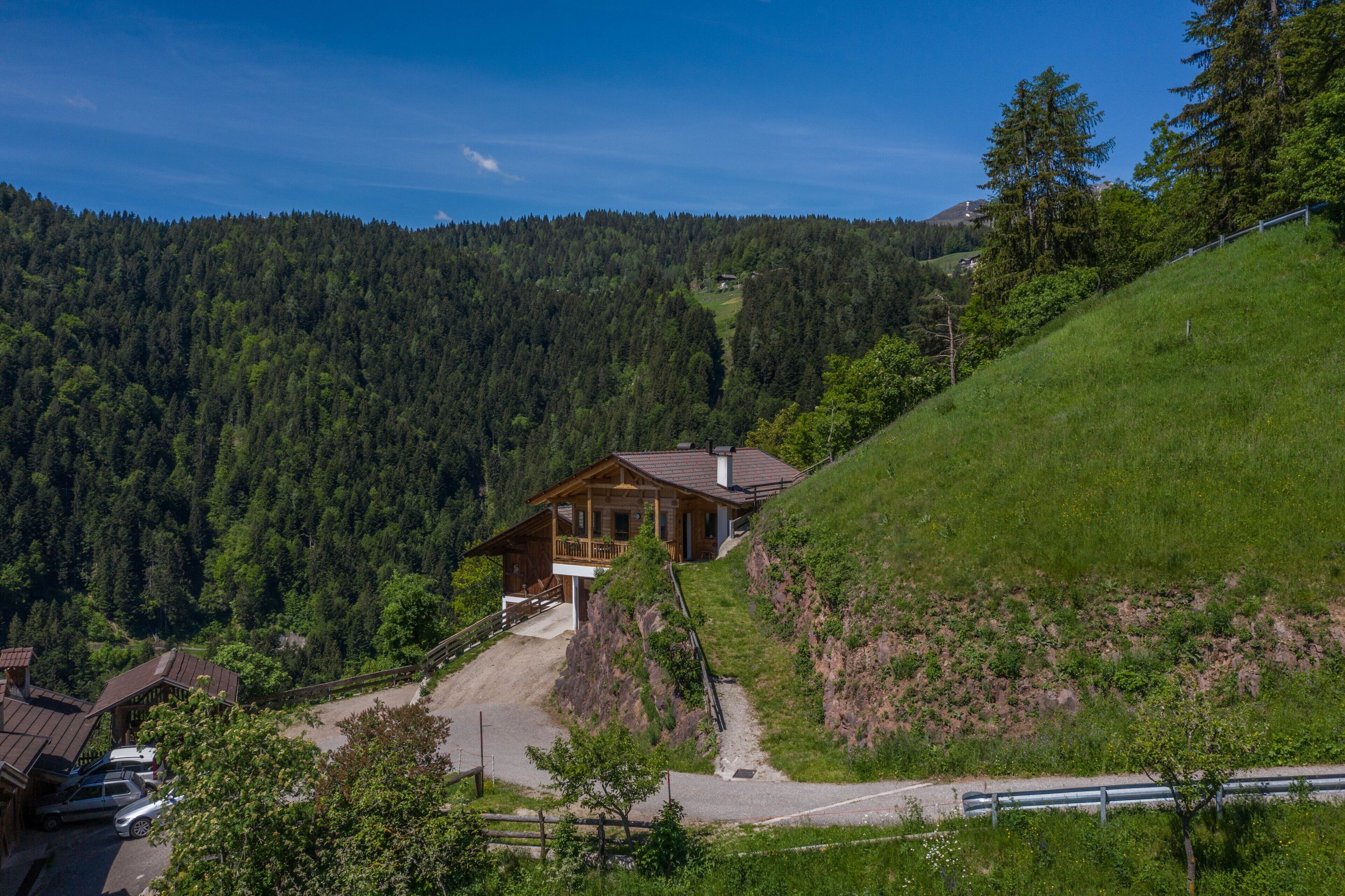 Eine Holzchalet mit Balkon, umgeben von bewaldeten Hügeln.