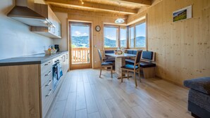 Un intérieur en bois comprenant une cuisine, un coin repas et de grandes fenêtres.