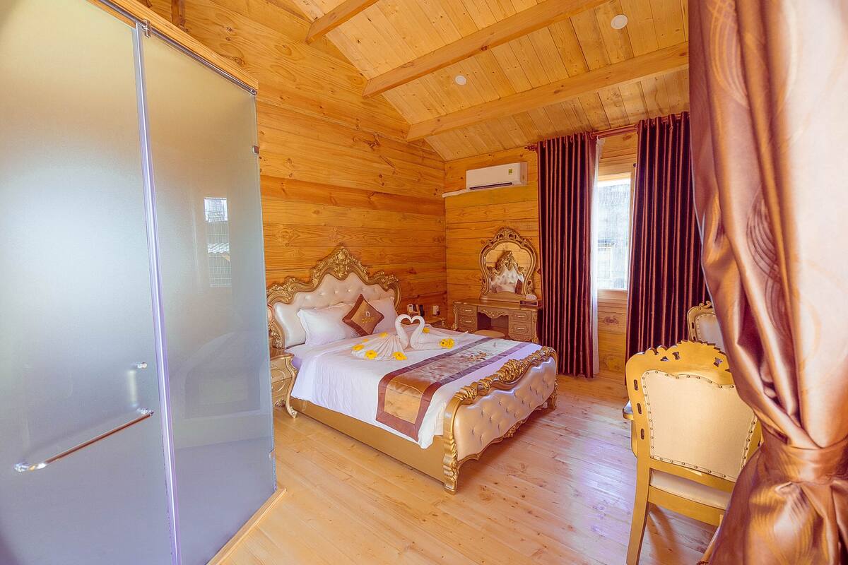 Quarto no estilo de cabana de madeira com uma cama, uma cadeira e um frigorífico.