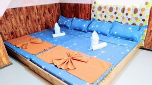 Un lit avec une couvre-lit bleue à motifs d’étoiles, des coussins décoratifs orange et une tête de lit en bois.