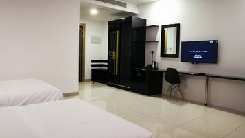 A hotel room with two beds, a TV, a desk, and a wardrobe.