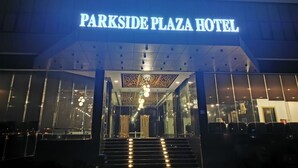 The exterior of the Parkside Plaza Hotel with a prominent illuminated sign, a modern entrance with glass doors, and a series of lights along the steps. - Parkside Plaza Hotel - Muscat (Muscat)