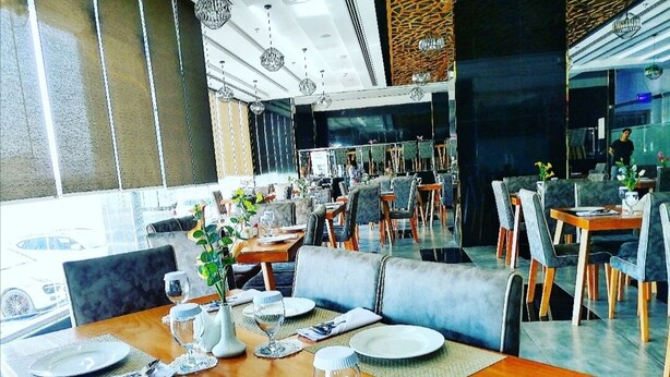 A restaurant with multiple dining tables set with plates, glasses, and cutlery. - Parkside Plaza Hotel - Muscat (Muscat)