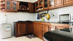 Una cocina con armarios de madera, un refrigerador, un microondas y una estufa.