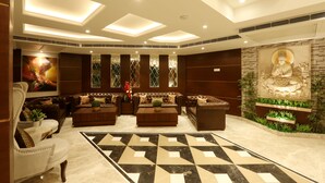 Een moderne lobby met een grote Boeddha-beeld, leren banken, een patroon vloer en een plafond met ingebouwde verlichting.