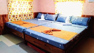 Een tweepersoonsbed met een blauw-oranje deken met sterafbeelding, twee kussens met stermotieven, en een gordijn met gele stippen.