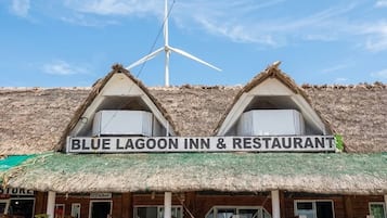 Ein Gebäude mit einem Schild, auf dem 'BLUE LAGOON INN & RESTAURANT' steht, und einer Windturbine im Hintergrund.