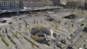 Ein großes, rundes Gebäude mit einem zentralen Innenhof, umgeben von einem geräumigen Platz mit Bäumen und Bänken.