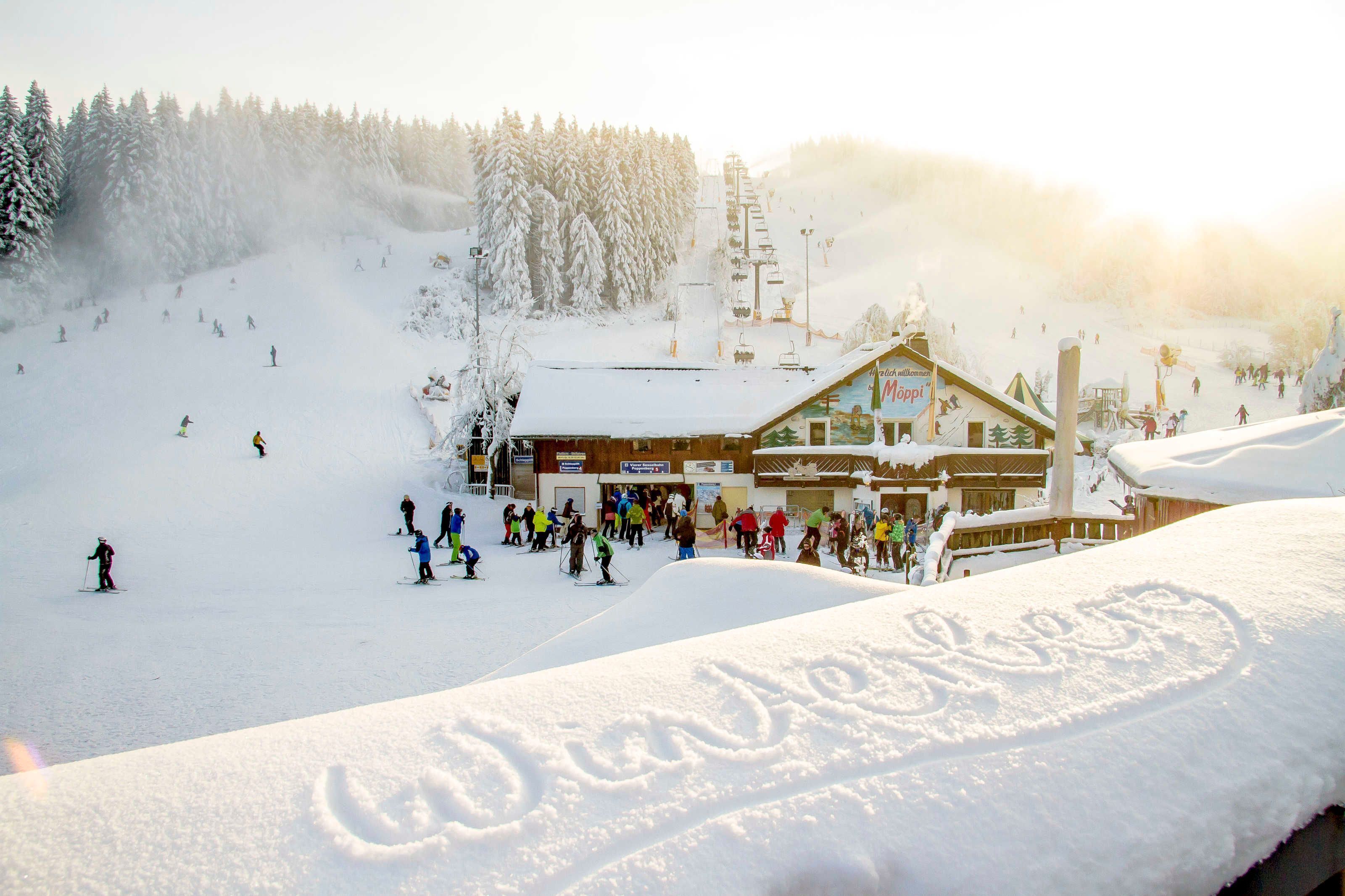 A ski resort with a lodge, snow-covered trees, and skiers.