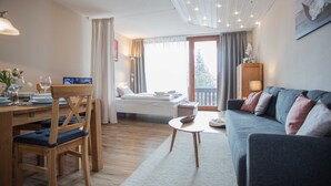 A well-lit room with a dining area, a sofa, and a bed. - Apartment Bike & Ski Kappe at the bike park / ski lift - Apartment Bike & Ski Kappe (Winterberg)