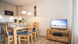 A modern kitchen with a microwave, coffee maker, and dining table set with chairs and a vase of flowers. - Apartment Bike & Ski Kappe at the bike park / ski lift - Apartment Bike & Ski Kappe (Winterberg)