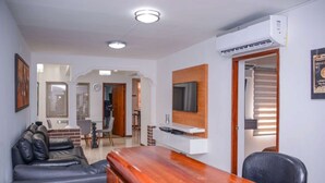 Un salon moderne avec une table basse en bois, un canapé en cuir et un téléviseur fixé au mur.