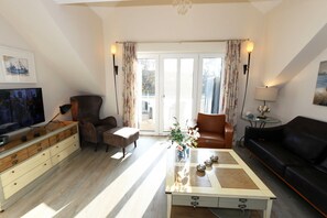 A living room with a television, a sofa, a coffee table, and a chair.