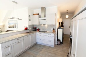 A modern kitchen with white cabinets, granite countertops, and stainless steel appliances.