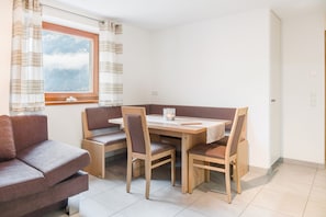 A dining area with a wooden table, four chairs, a bench, and a sofa.