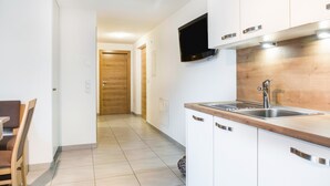 A modern kitchen with a wooden countertop, stainless steel sink, and a flat-screen TV mounted above the counter. - Holiday Apartment "Hofschenke Pfeiftal Almenrausch" with Terrace, Garden & Wi-Fi (St. Martin in Passeier)
