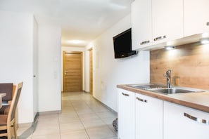 A modern kitchen with a wooden countertop, stainless steel sink, and a flat-screen TV mounted above the counter. - Apartment “Hofschenke Pfeiftal Almenrausch” with Terrace, Garden & Wi-Fi (St. Martin in Passeier)