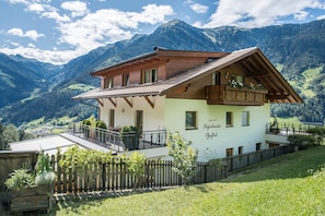A chalet with a balcony, wooden fence, and a view of mountains.