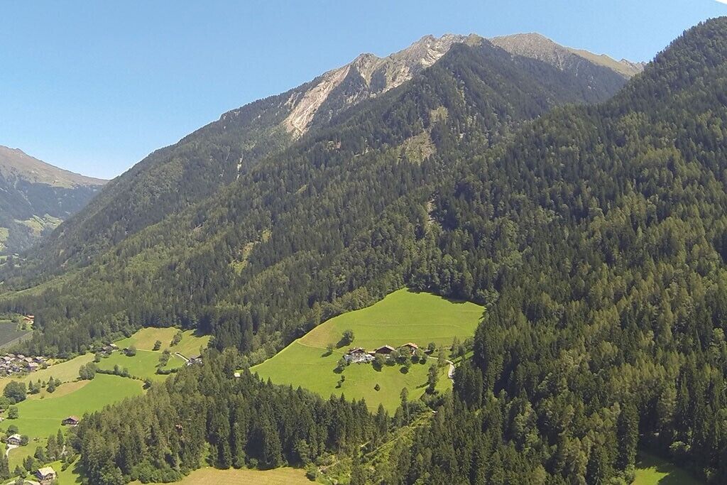 Eine gebirgige Landschaft mit grünen Feldern und verstreuten Gebäuden.