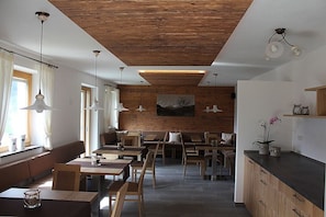 A modern interior with wooden ceiling, dining area, seating, and a kitchen counter. - Apartment “Hofschenke Pfeiftal Almenrausch” with Terrace, Garden & Wi-Fi (St. Martin in Passeier)