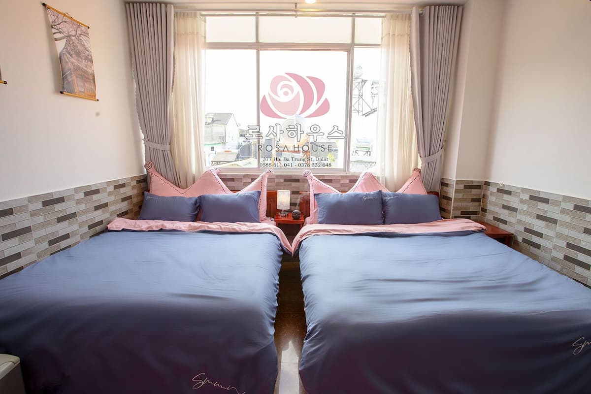 Habitación de hotel con dos camas, una ventana con cortinas y vistas al exterior.