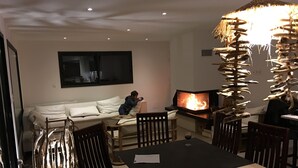 Ett vardagsrum med en soffa, en tv och en öppen spis.