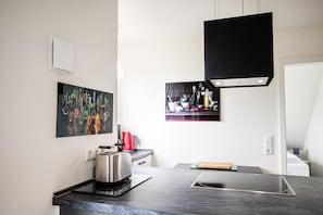 A modern kitchen with a built-in stove, a coffee maker, and two framed pictures on the wall.