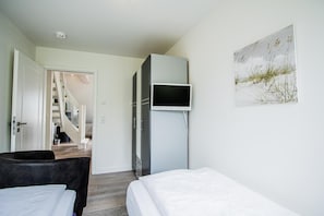 A bedroom with two beds, a TV, and a painting on the wall.