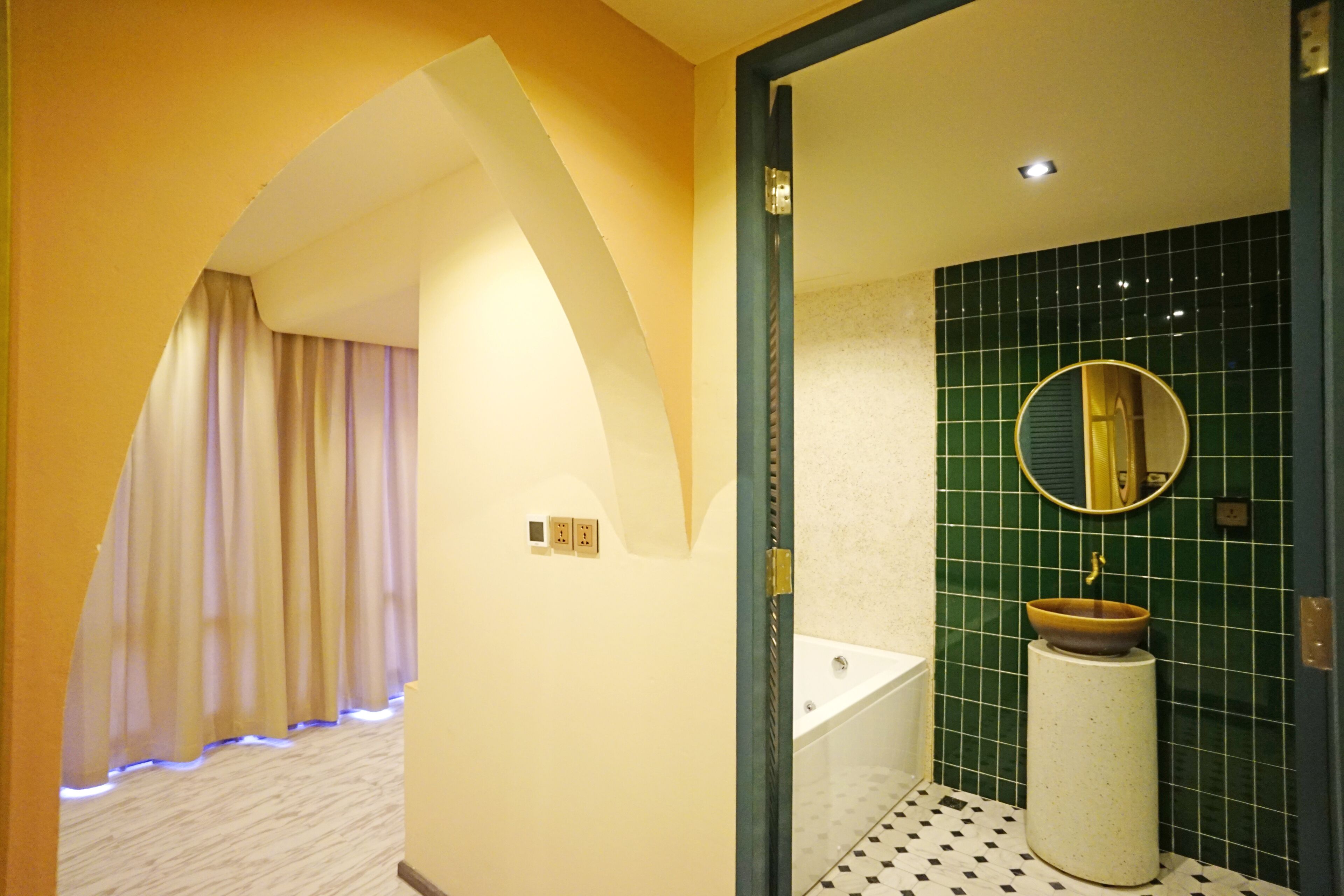 Une salle de bain avec une baignoire, un lavabo, un miroir et un mur recouvert de carreaux.