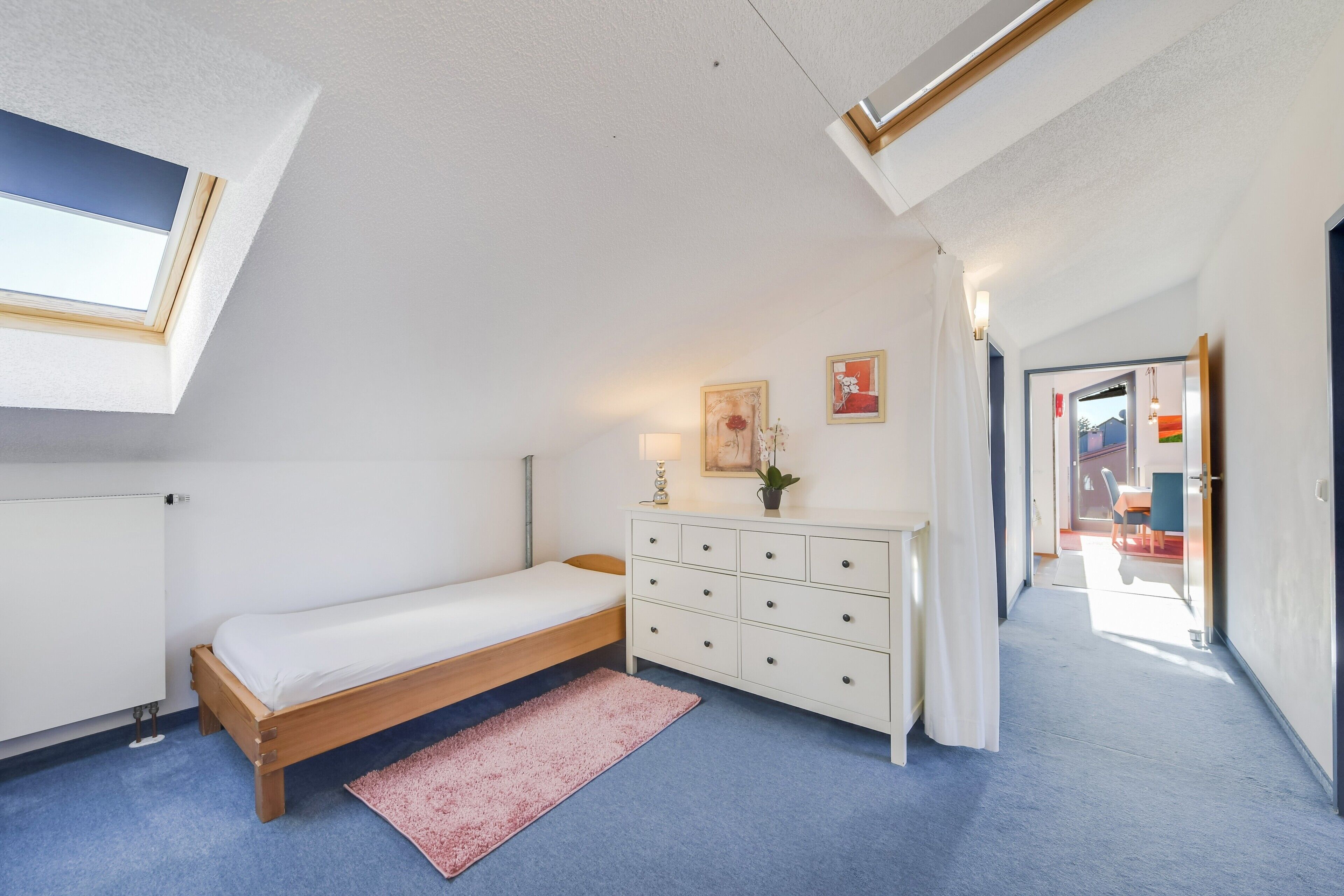 Ein Schlafzimmer mit einem Einzelbett, einem Schminktisch, einem Heizkörper und einem Dachfenster.