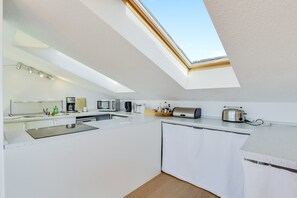 A modern kitchen with a skylight, white cabinetry, and a built-in oven.