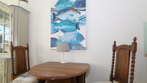A dining table with two chairs, a lamp, and a wall-mounted painting of fish. - Sylt breeze <br>Wenningstedt on the beach (Wenningstedt)