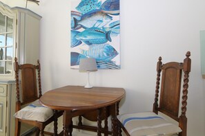 Ein Esstisch mit zwei Stühlen, einer Lampe und einem an der Wand hängenden Bild von Fischen.