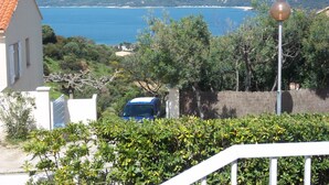 A coastal view with a house, a blue car, and a clear blue sea. - Semi-detached Villa Sea View - Private Parking - Near Town Center and Beaches (Propriano)