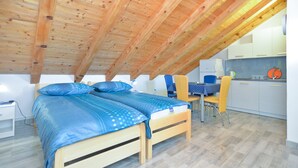 A cozy attic bedroom with two wooden beds, a small kitchenette, and a dining area. - Apartment 1713/17699 (Istria - Valbandon), 200m from the beach (Valbandon)