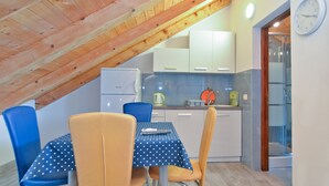 A small kitchen with a wooden ceiling, a dining table with chairs, and a clock on the wall. - Apartment 1713/17699 (Istria - Valbandon), 200m from the beach (Valbandon)